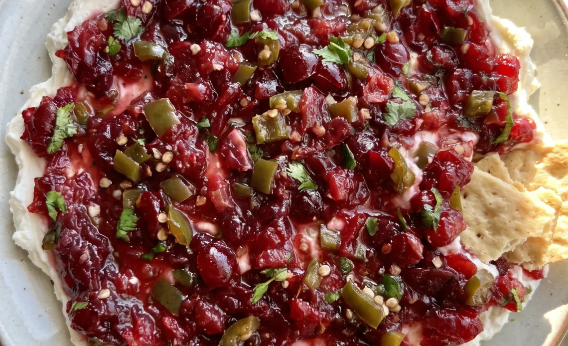 Cranberry jalapeno cream cheese dip topped with chopped cranberries, jalapeno slices, cilantro, and green onion.