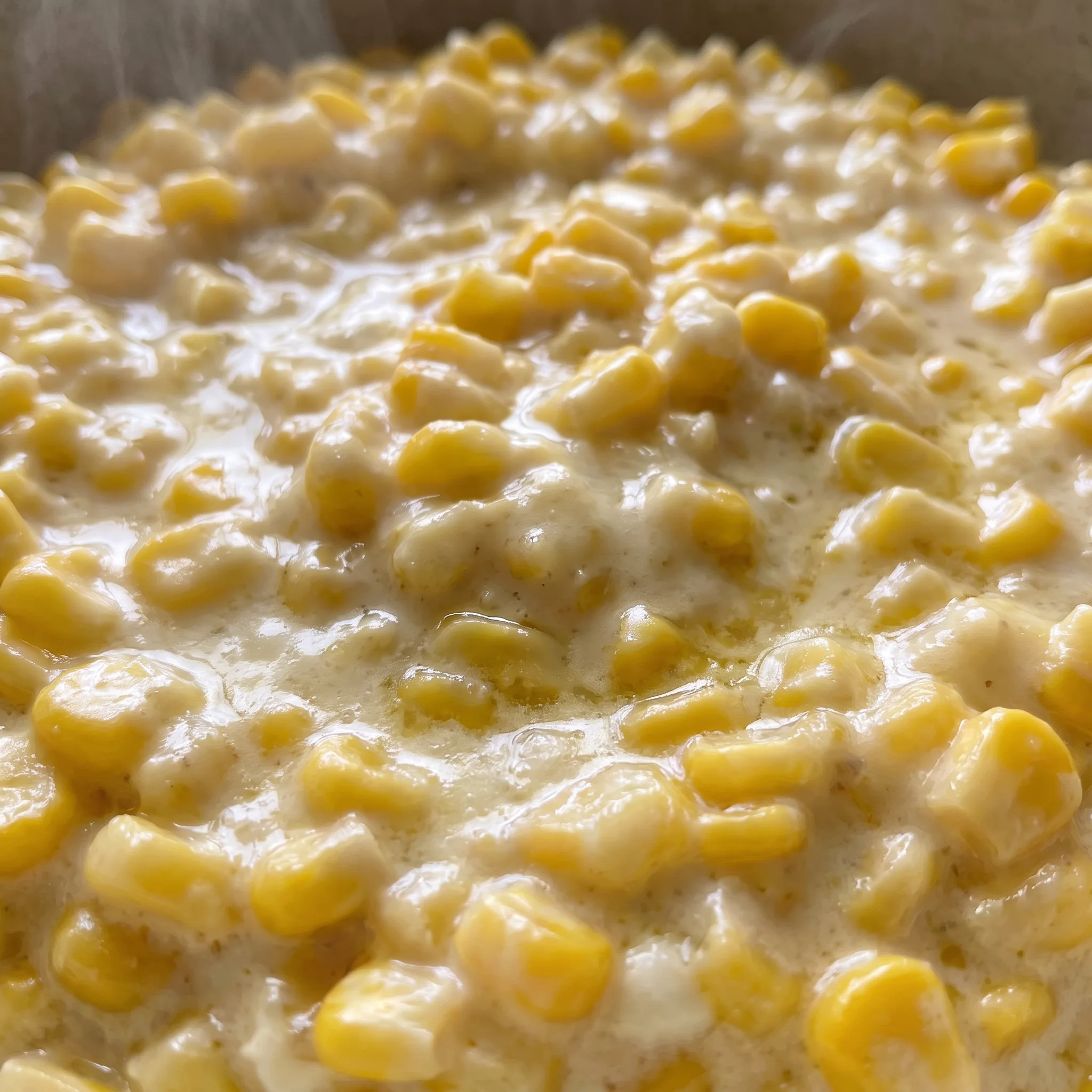 Glossy corn kernels coated in a rich, creamy sauce with melted butter.