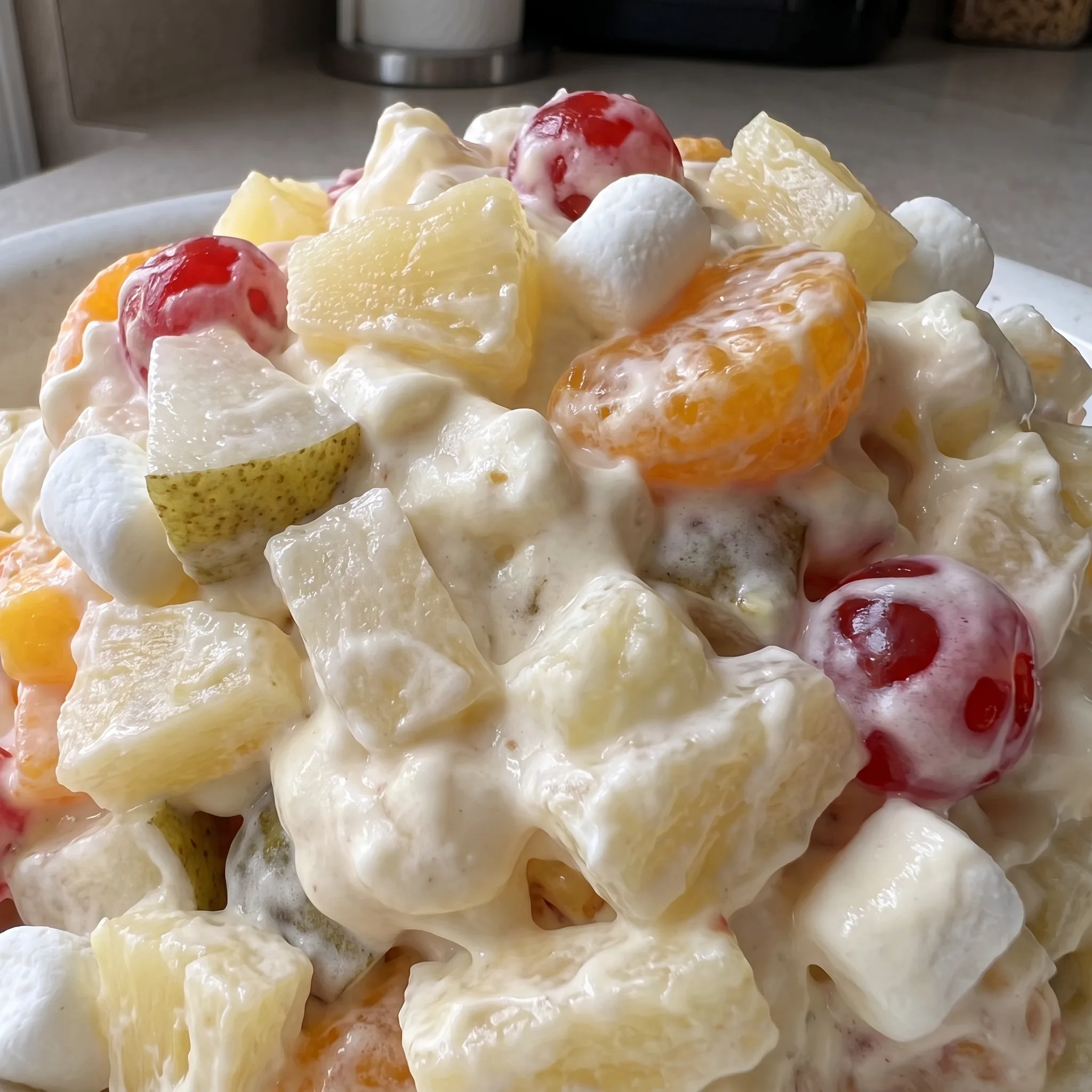Creamy whipped topping with soft mini marshmallows, orange segments, pineapple chunks, and red cherries.