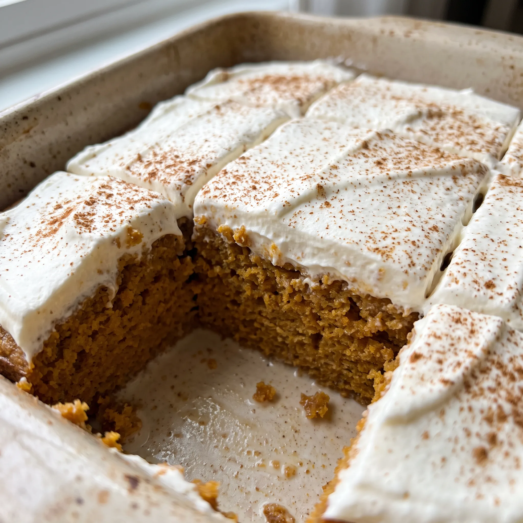 Pumpkin tres leches cake with whipped cream and a dusting of cinnamon.