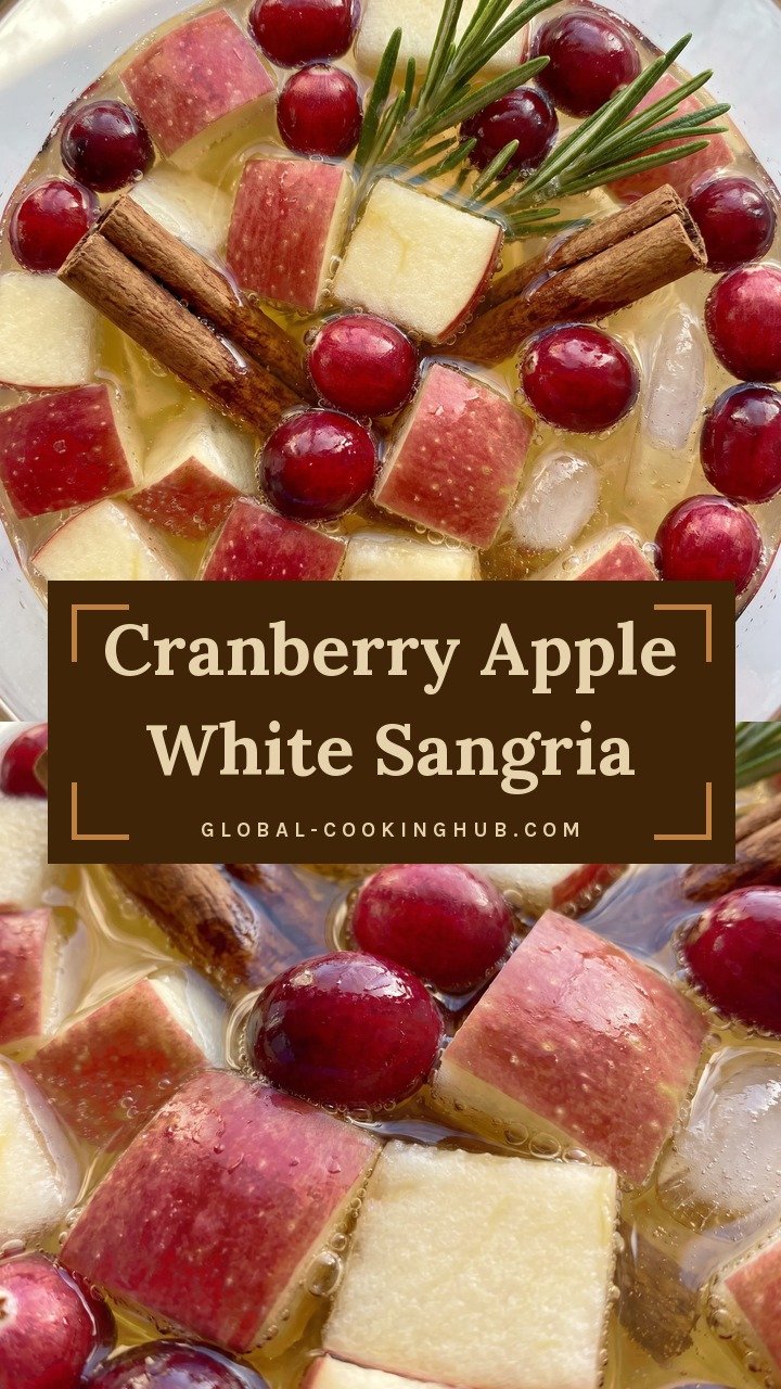 White wine sangria with whole red cranberries, cubed red apple, cinnamon sticks, and rosemary sprigs in a clear ruby liquid.