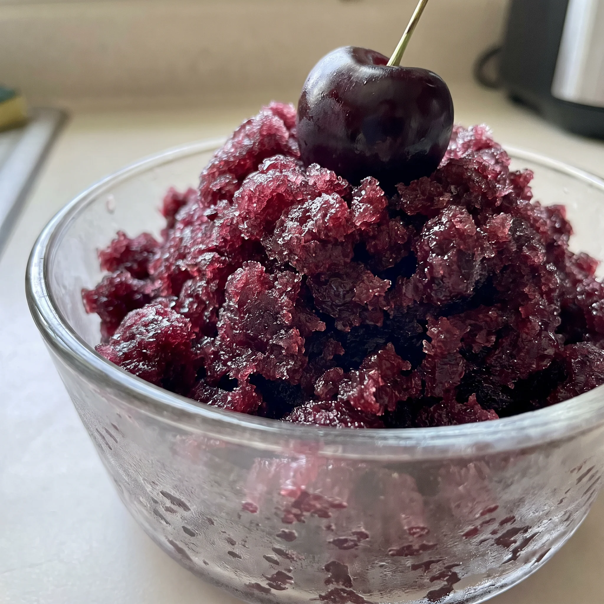 Black cherry granita with dark red cherry pieces and pale ice crystals, showing a coarse, icy texture.