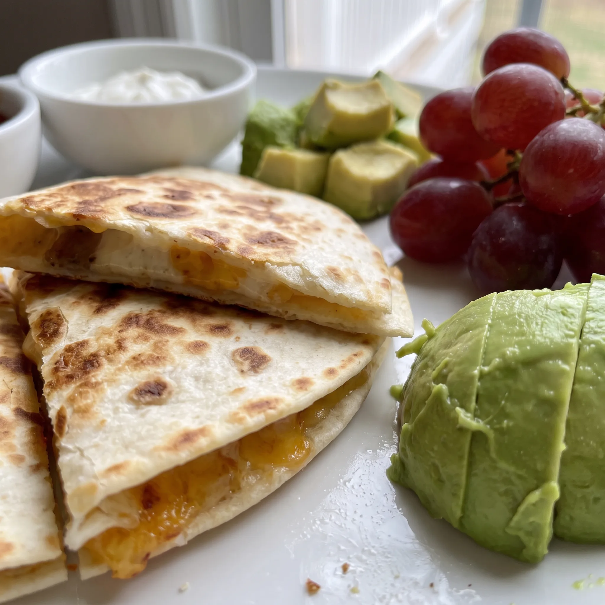 Golden toasted tortilla wedges with gooey melted cheese, creamy avocado, and glossy red salsa.