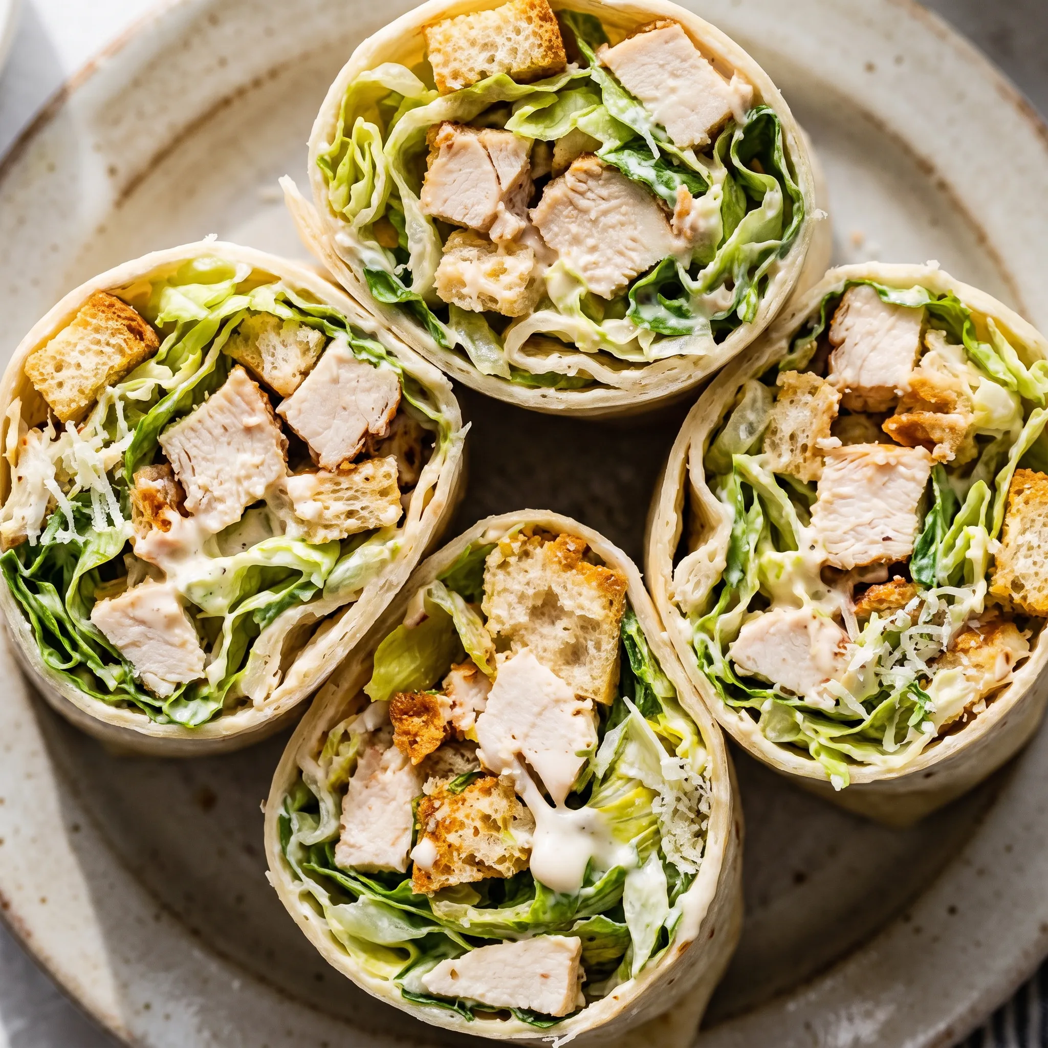 Chicken Caesar wraps with romaine lettuce, cooked chicken, Caesar dressing, Parmesan cheese, and croutons in flour tortillas.