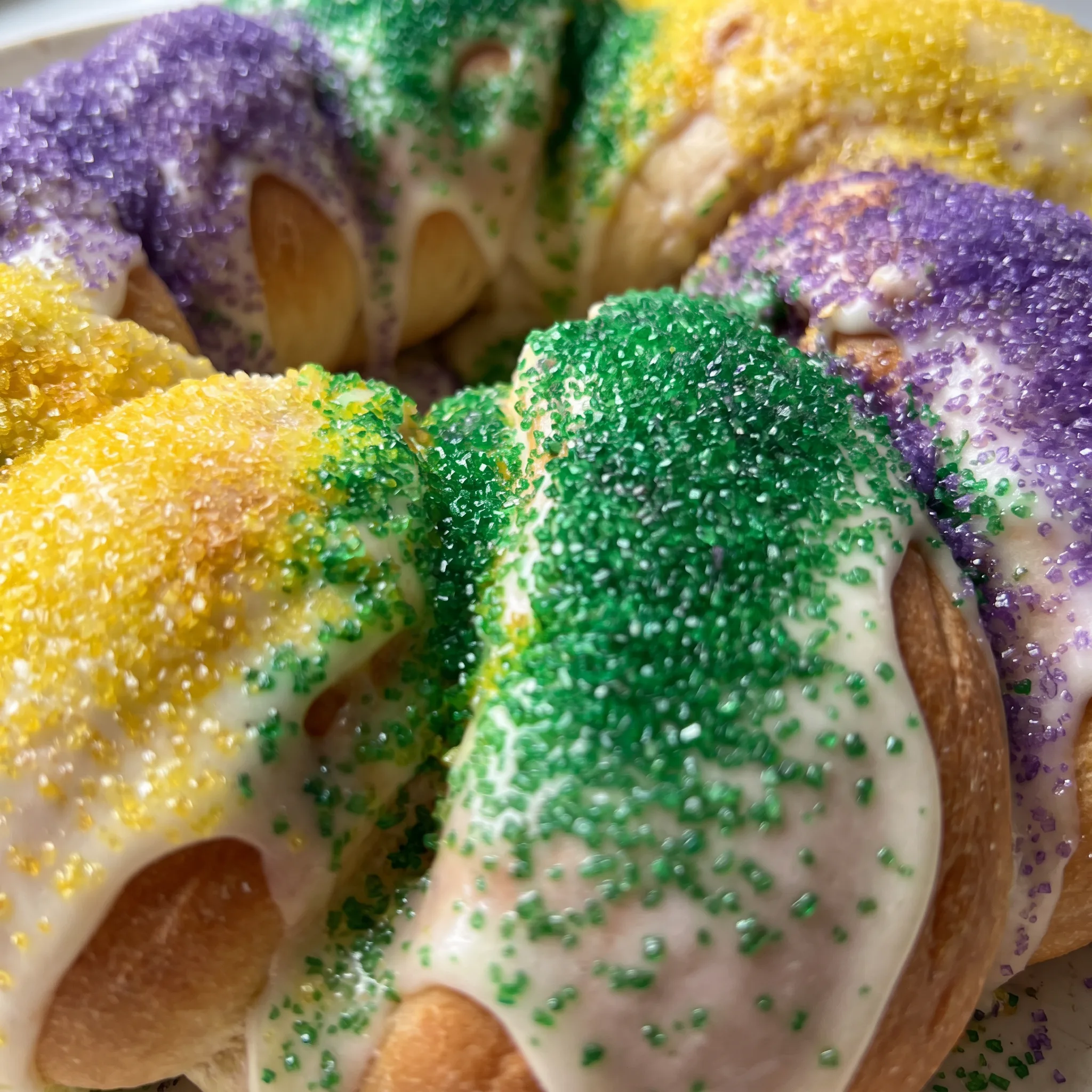 Cinnamon-swirled cream cheese filling inside a frosted cake slice, topped with purple, green, and gold sugar.