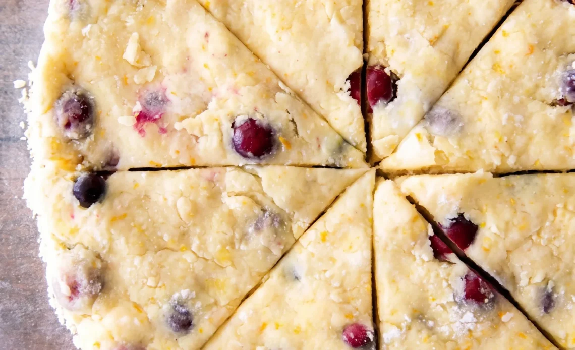 Cranberry orange scones with red berries and orange zest, drizzled with orange glaze.