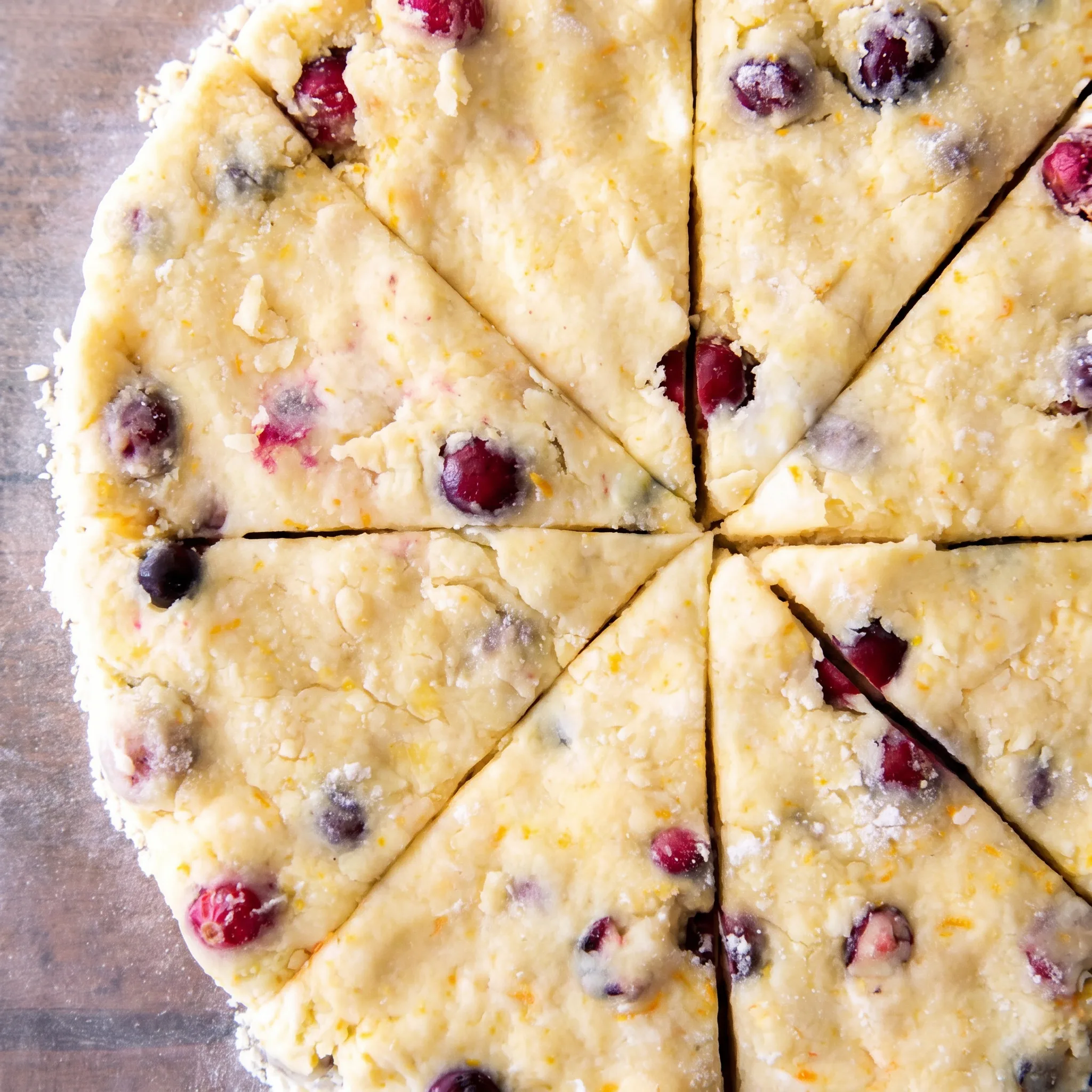 Cranberry orange scones with red berries and orange zest, drizzled with orange glaze.