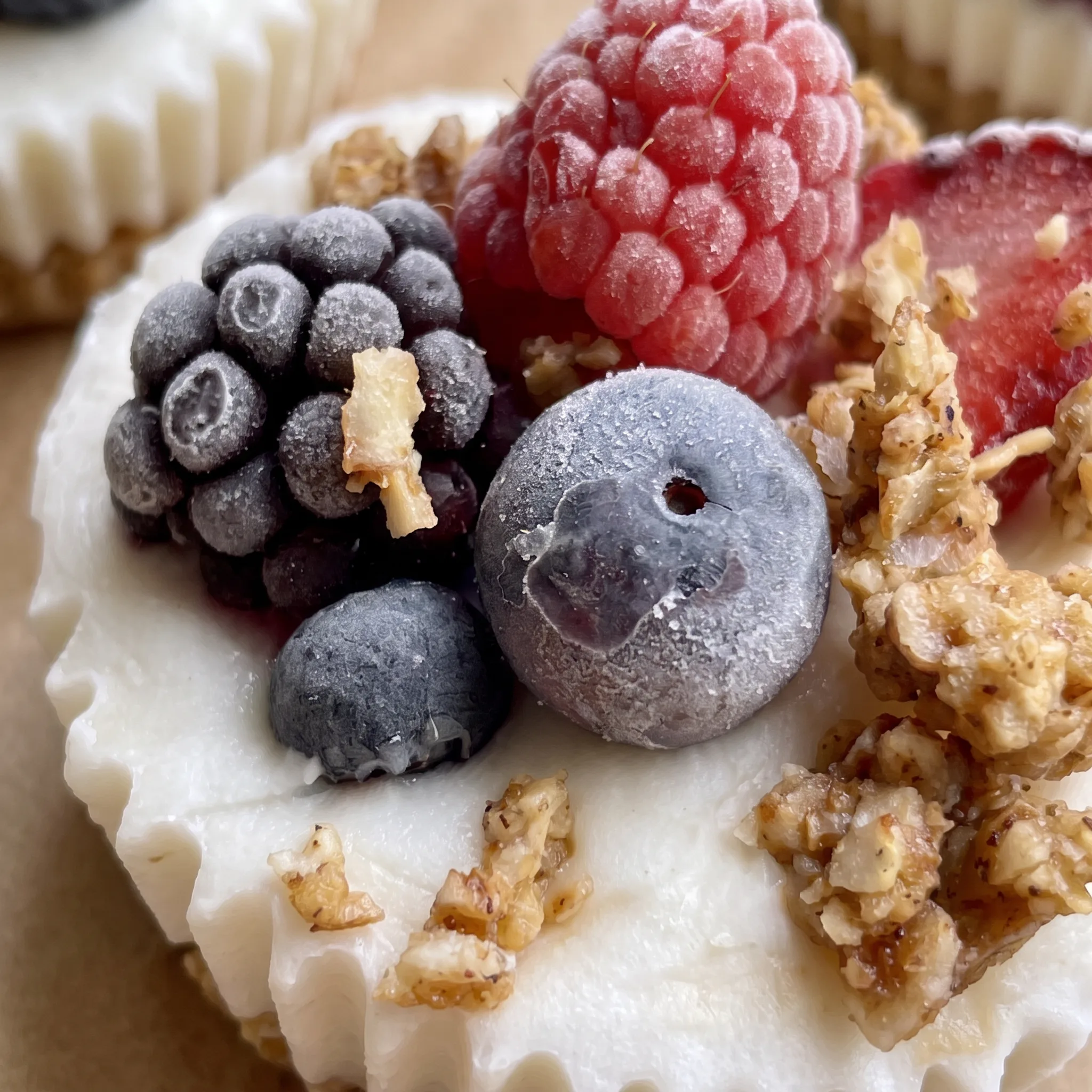 Creamy white yogurt with a crunchy golden granola base and glossy red and blue berries.