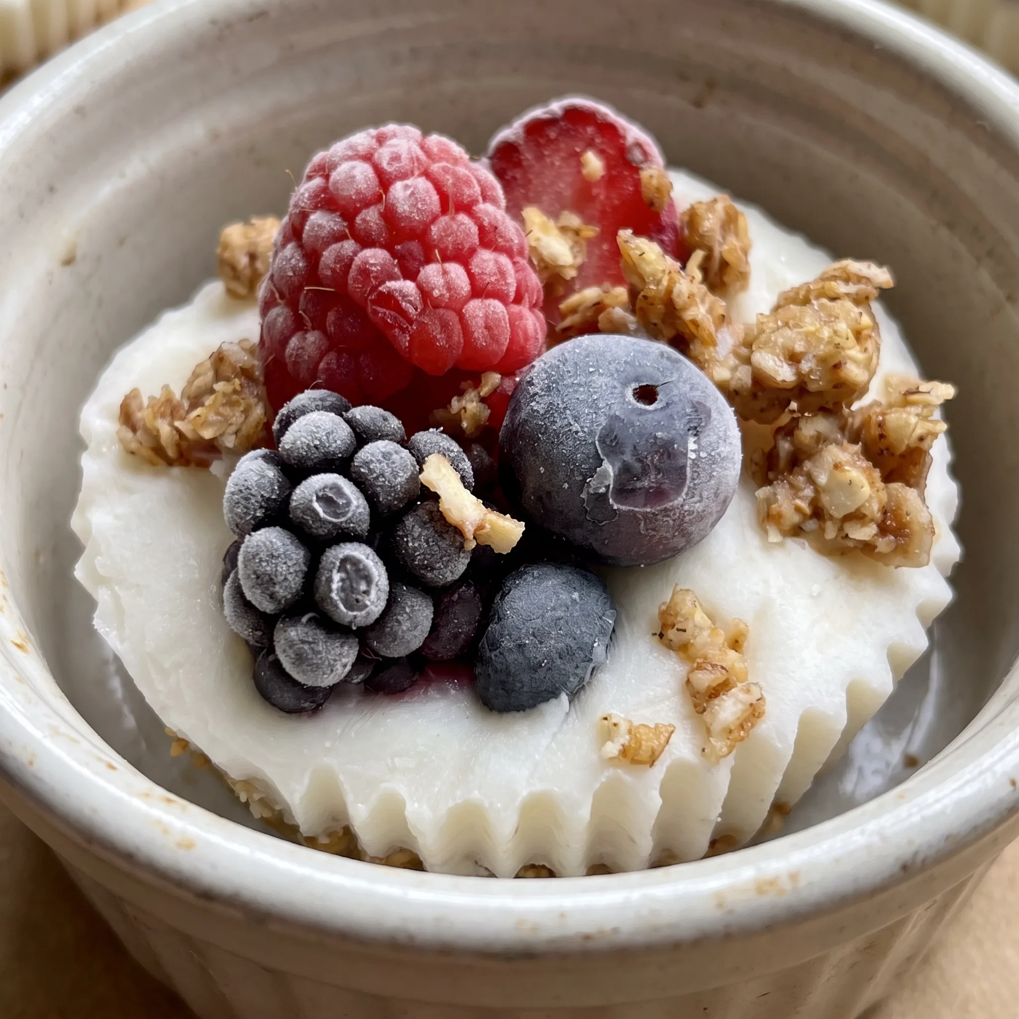 Frozen yogurt granola cups filled with Greek yogurt and topped with mixed berries.