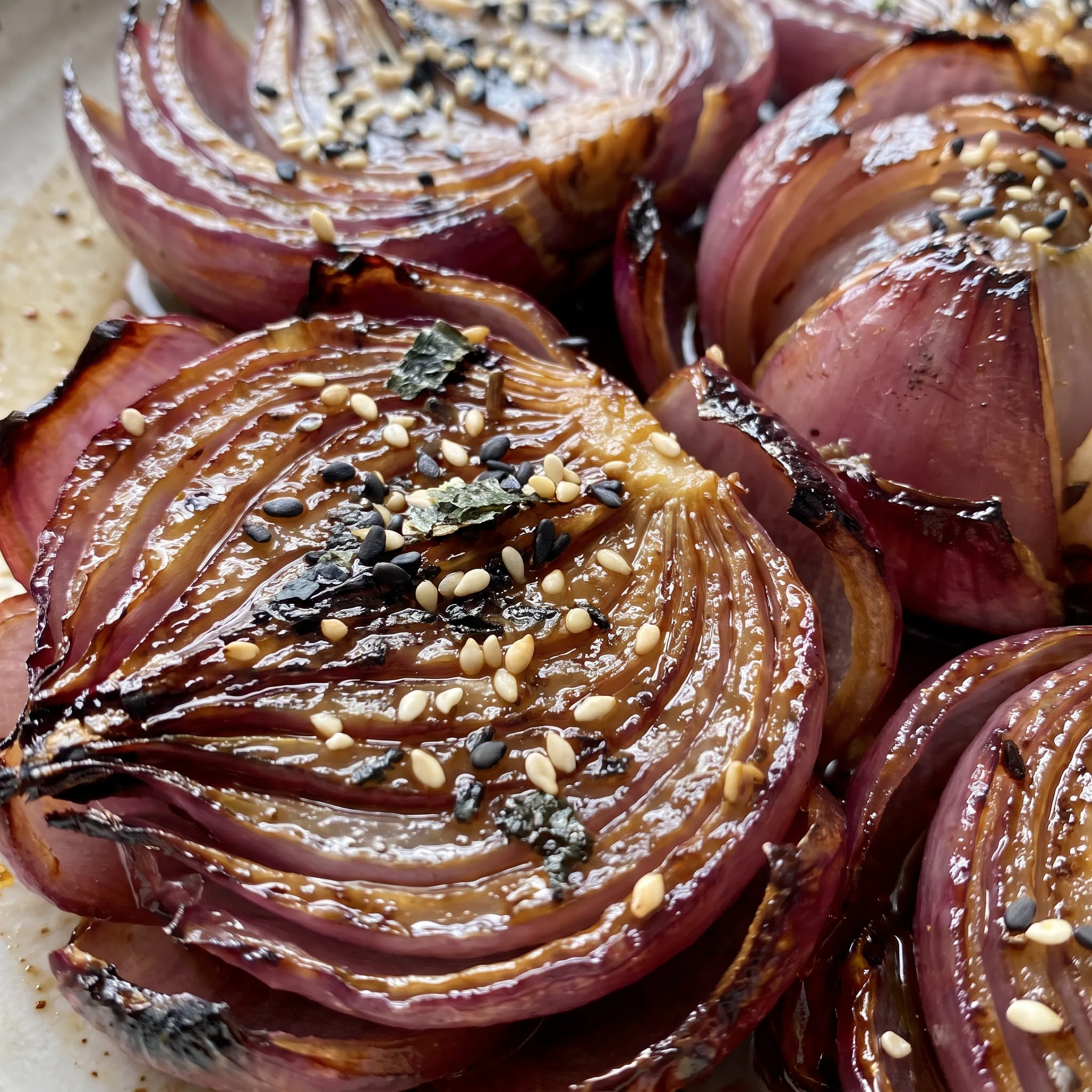 Glossy caramelized red onion petals with a sticky honey-vinegar glaze, sprinkled with speckled furikake.