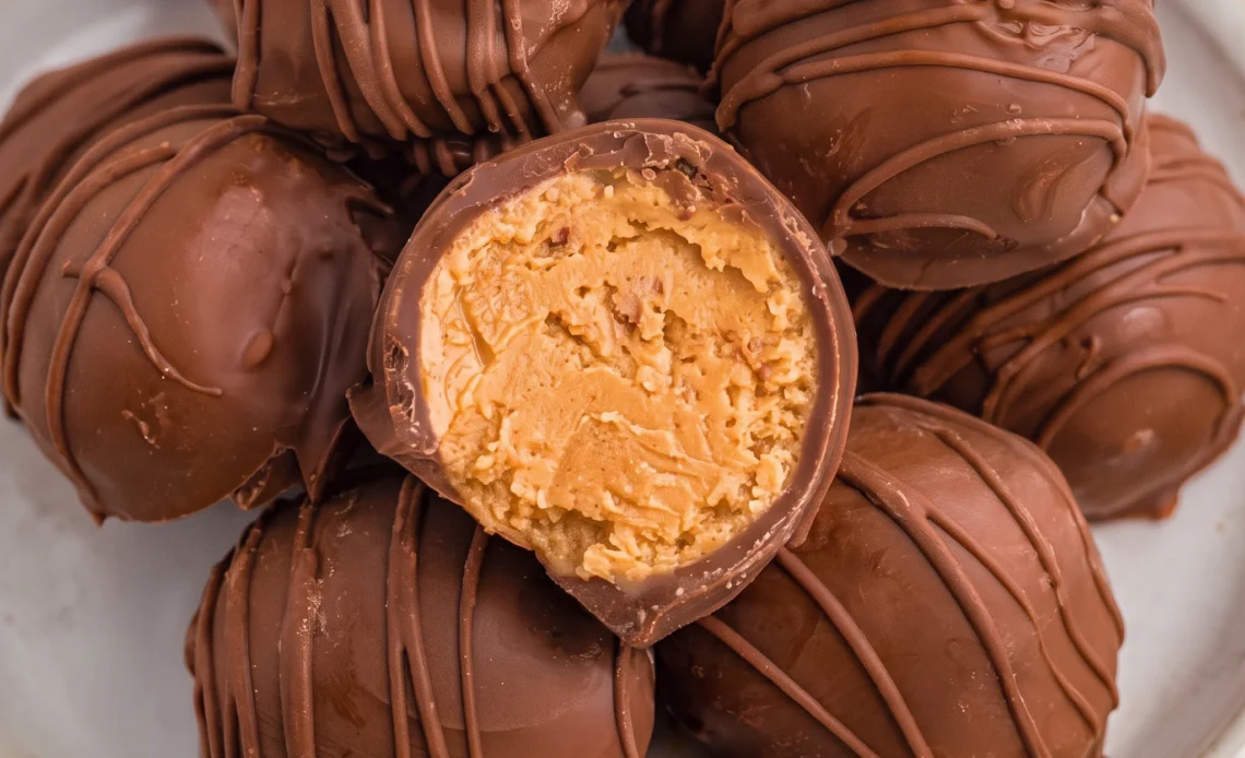 Round peanut butter balls coated in a smooth chocolate shell, arranged together in even rows.