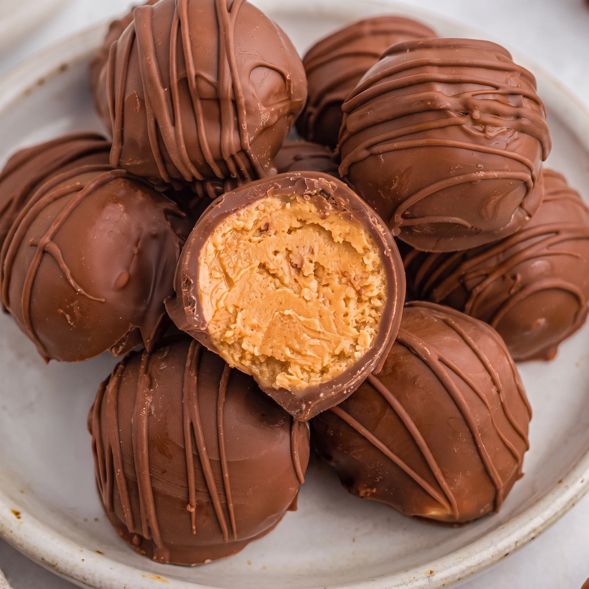 Round peanut butter balls coated in a smooth chocolate shell, arranged together in even rows.
