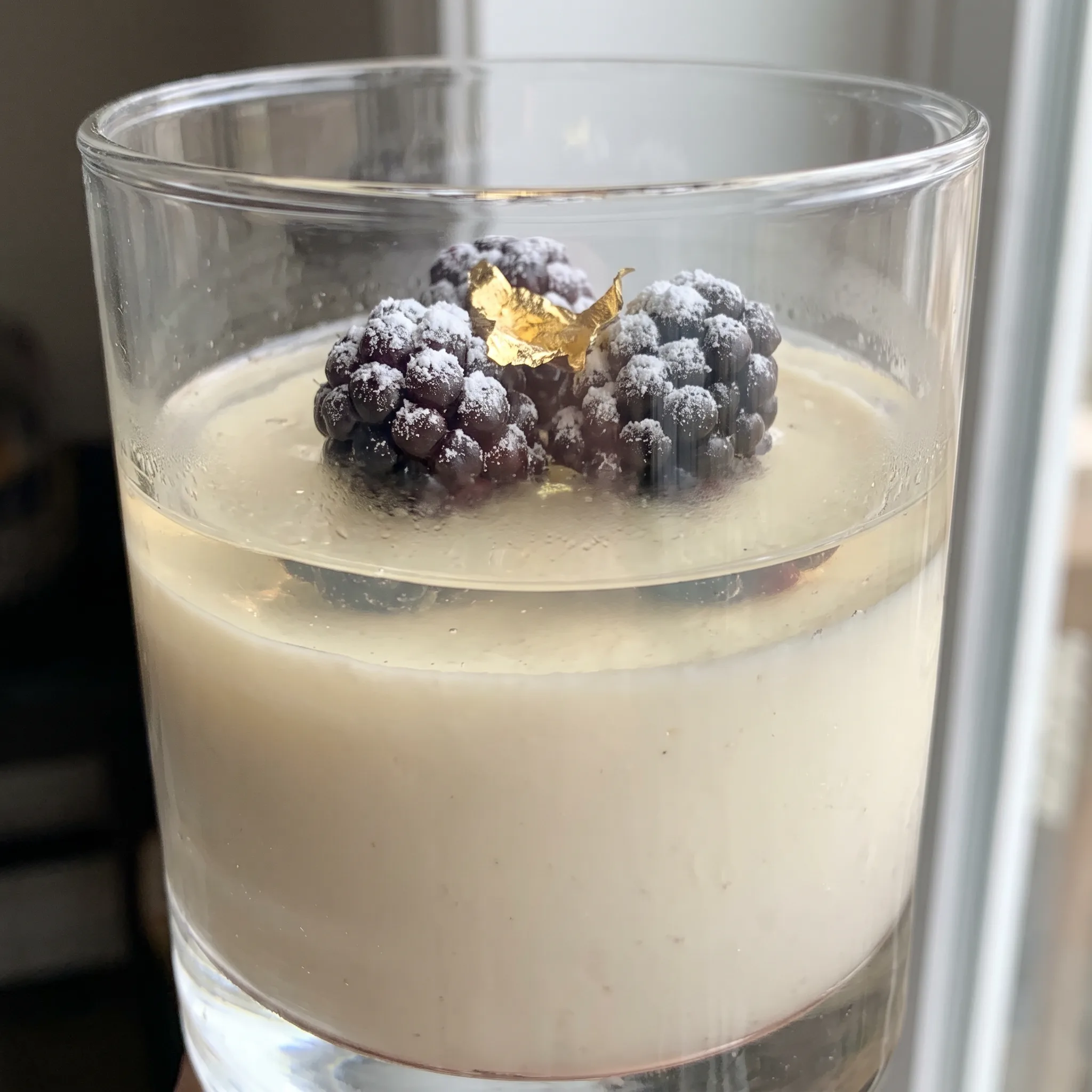 Sparkling wine panna cotta topped with fresh raspberries and blackberries, pale cream custard with glossy red and dark purple fruit.